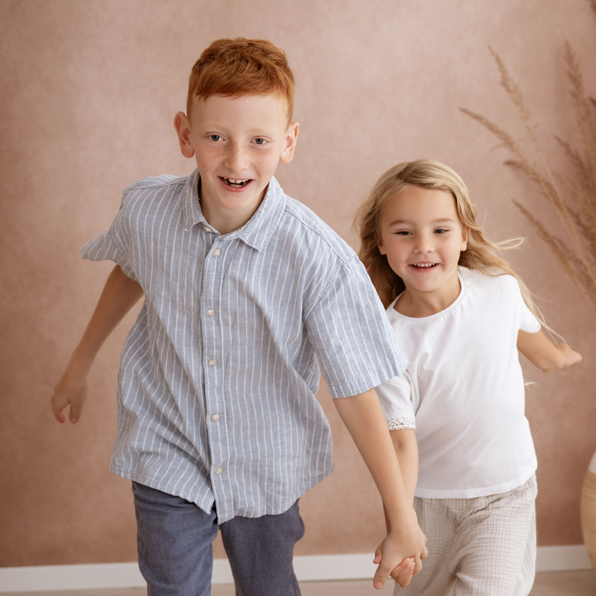 Bruder und Schwester laufen lachend durchs Studio