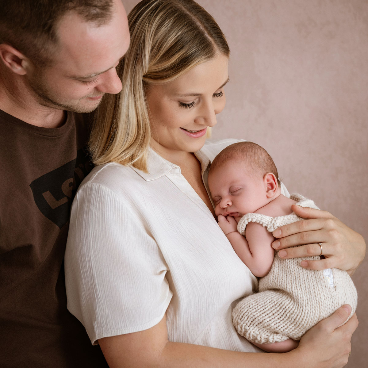 Mama und Papa halten ihr Neugeborenes im Arm
