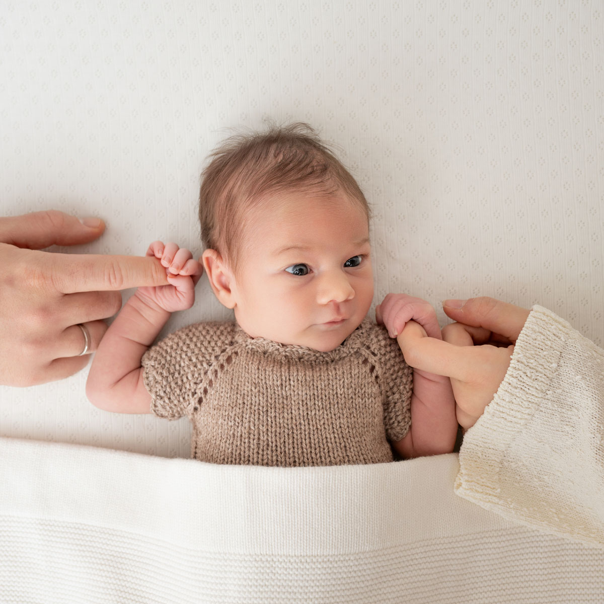 Waches Baby hält die Finger seiner Eltern