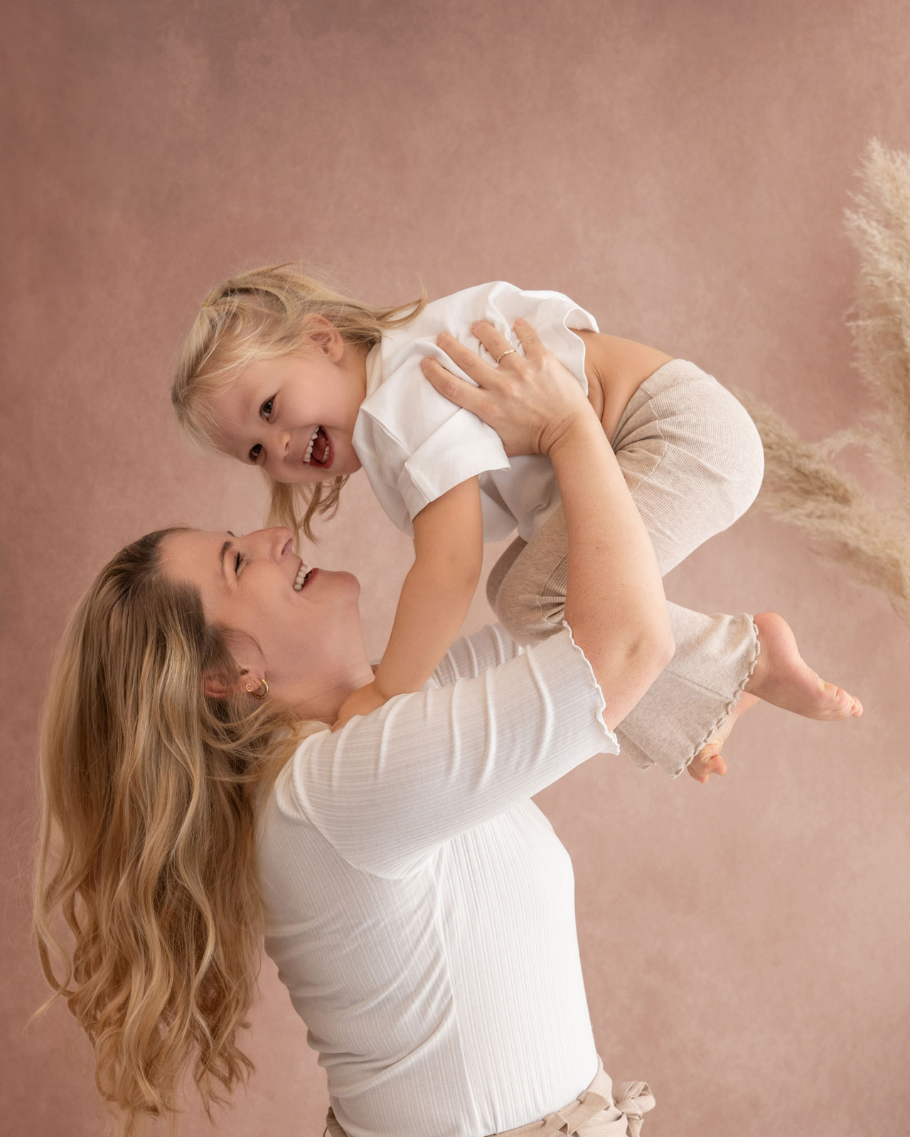 Mama hebt ihr lachendes Kind in die Luft