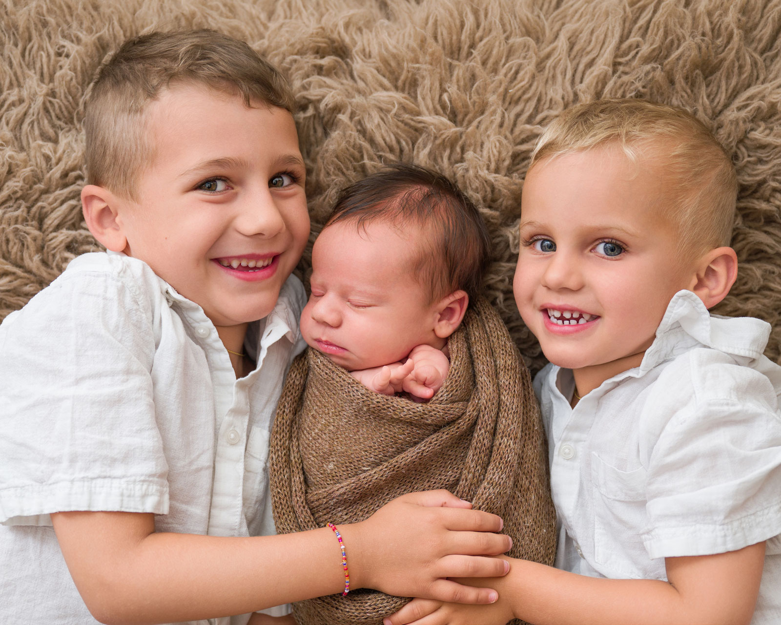 Drei Geschwister kuscheln beim Fotoshooting